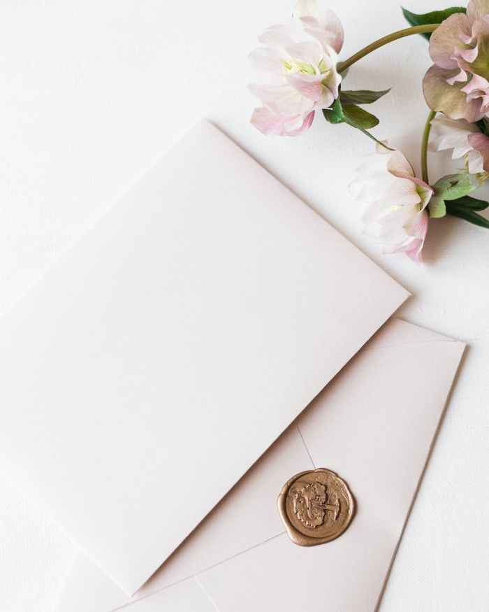 two white envelopes and flowers laying on white surface