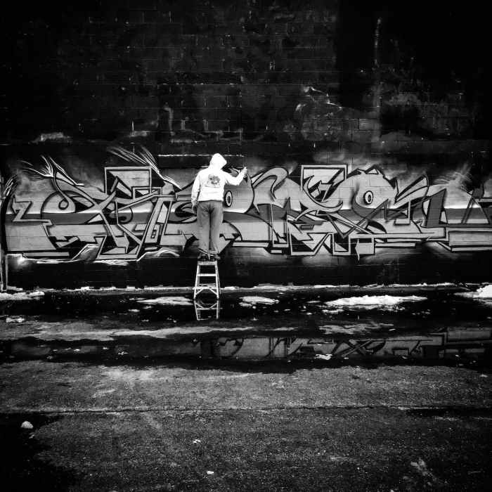 grayscale photo of person doing graffiti