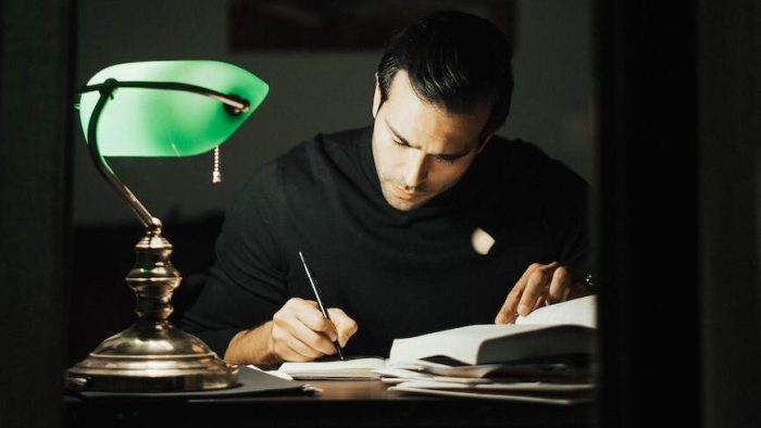 thoughtful man writing in notebook and studying in home office